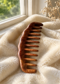 Wooden comb on a soft, textured surface with a window in the background