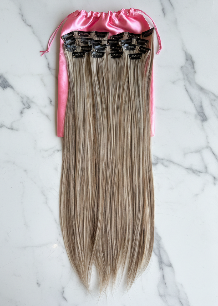 Blonde hair extensions in a pink packaging on a marble surface